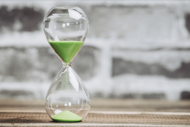 Hourglass with green sand highlighting time decay in options trading and shrinking option value.